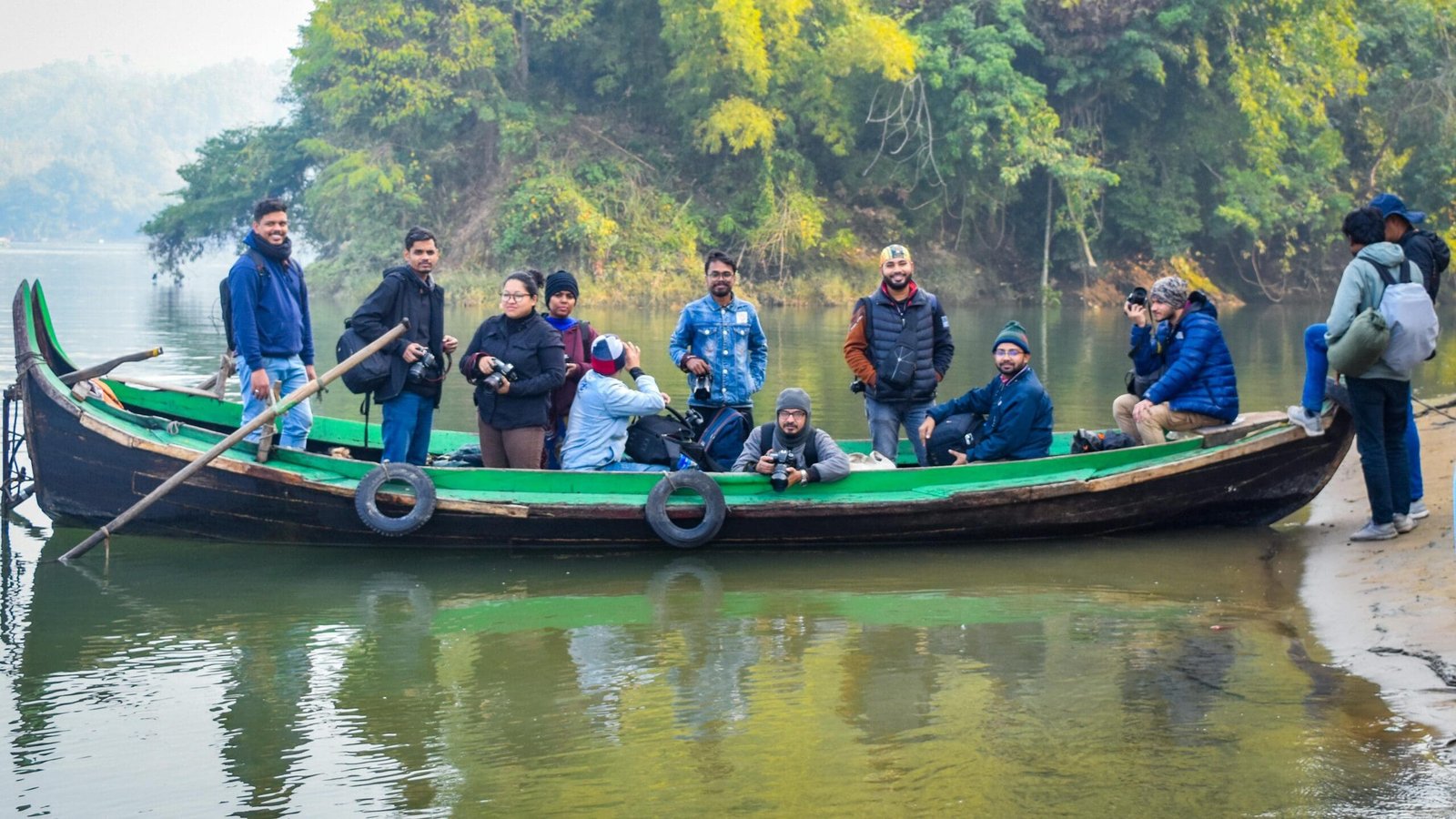 A group of tourists with cameras enjoying a boat ride in a scenic, rural area.