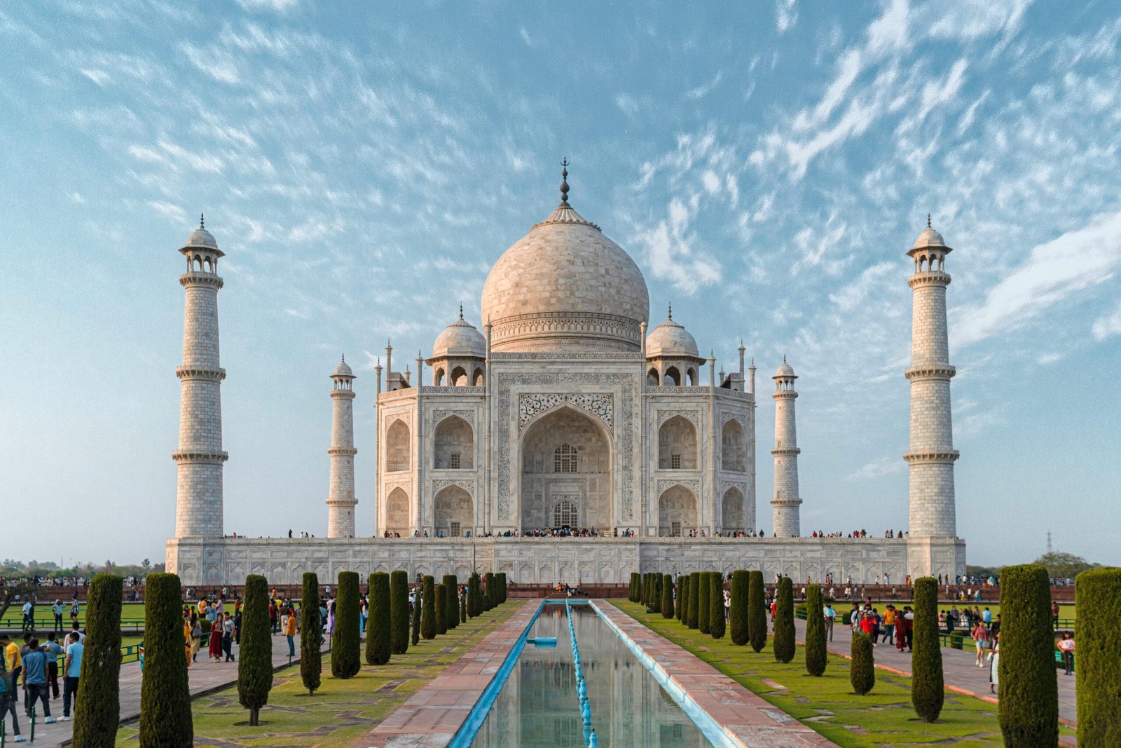 Front view of the Taj Mahal, showcasing its iconic architecture against a blue sky.